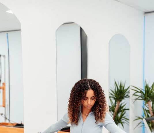 필라테스가 불러오는 체형 교정과 정신 건강 개선 효과 a woman sitting on a piyor in a gym