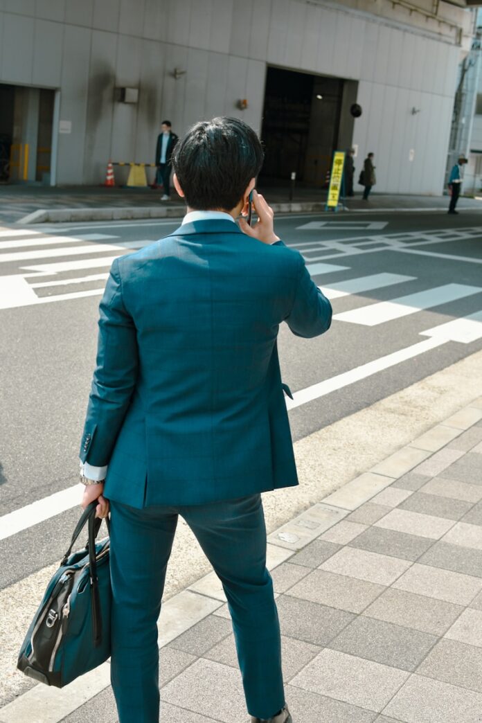 A businessman talks on the phone while crossing the street.