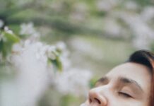 숨만 잘 쉬어도 인생이 바뀐다, 의식적인 호흡 수련 a woman with her eyes closed and a flower in her mouth