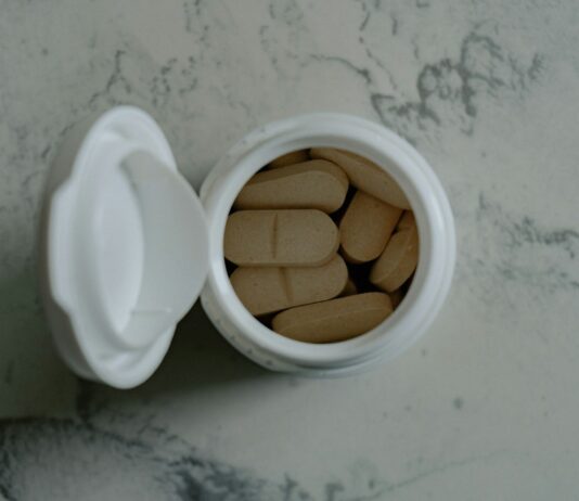 맞춤 영양 보충제, 내 몸에 꼭 맞는 섭취 방법 찾기 Opened bottle of beige pills on marbled surface