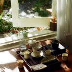 바쁜 일상 속 정신건강 챙기기, 작은 변화가 만드는 큰 차이 Tea set arranged on a wooden tray by the window.