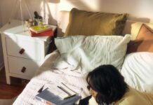 바쁜 직장인, 작은 변화로 건강 챙기기…“책상 앞 루틴이 답이다” Woman working on laptop on bed with snacks and books.