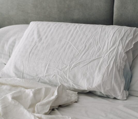 수면의 질 높이는 생활 습관 변화, 실천이 답이다 A rumpled white duvet and pillows on a bed.