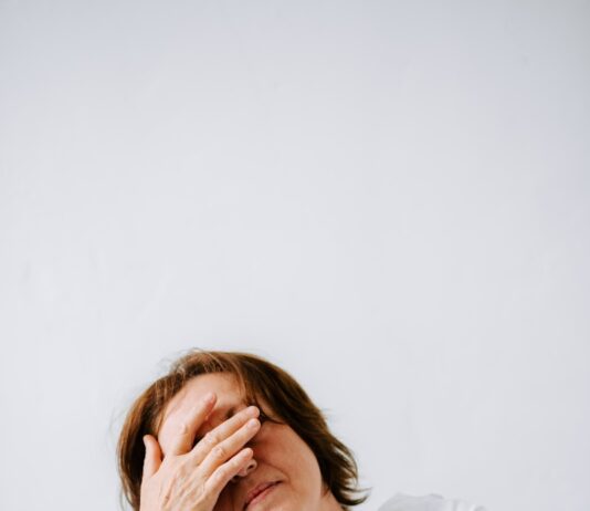 “만성피로, 단순한 피곤함 넘어서 — 최신 연구와 트렌드로 바라본 똑똑한 관리법” a woman sitting on a couch holding her hands to her face