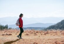 “저녁 산책, 달라지는 일상: 작은 움직임이 주는 큰 변화” a man with a backpack walking across a dry grass covered field
