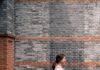 일상 속 걷기, 건강을 지키는 가장 손쉬운 비결 A woman walks along a brick wall.