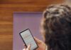 ‘웰니스 문화’, 한국인의 일상에 스며든 건강한 변화 Woman using a smartphone on a yoga mat.